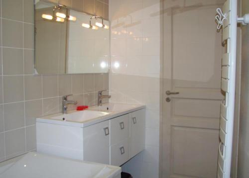 a white bathroom with a sink and a mirror at Le gite communal in Puilly-et-Charbeaux