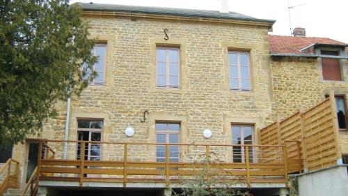 a large brick building with a wooden deck in front of it at Le gite communal in Puilly-et-Charbeaux