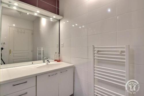 a white bathroom with a sink and a mirror at Les hortensias in Feins