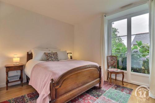 a bedroom with a bed and a large window at Les hortensias in Feins