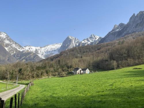 a house in a field with mountains in the background at Grand aoulet in Accous