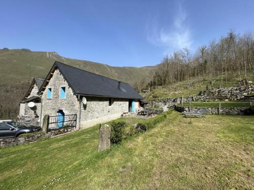 a stone house on a hill with a car parked next to it at Grand aoulet in Accous