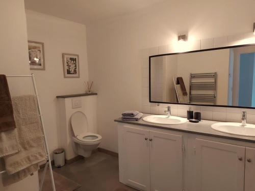a bathroom with a toilet and two sinks and a mirror at Aux couleurs du lac in Géraudot