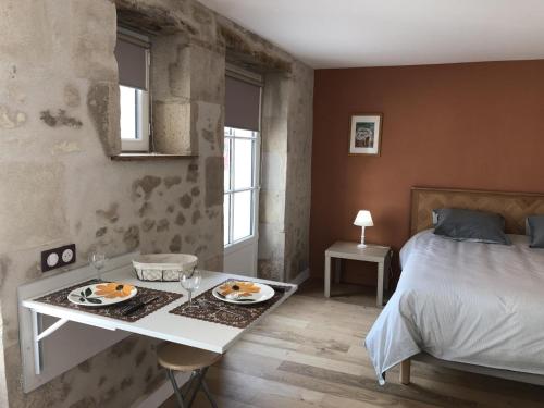 - une chambre avec un lit et une table avec des assiettes de nourriture dans l'établissement Le studio de saint-maixent le petit, à Haims