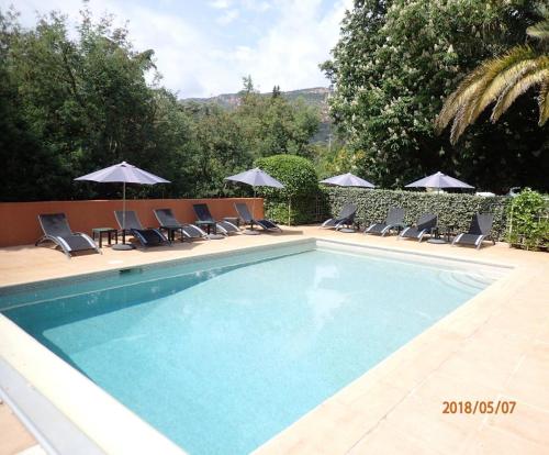 une piscine avec chaises et parasols dans l'établissement Le murier a la bouverie, à Roquebrune-sur Argens