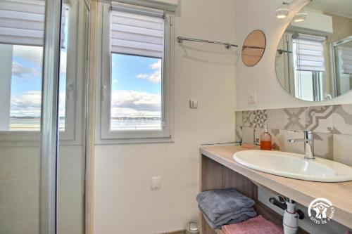 ein Badezimmer mit Waschbecken, Spiegel und Fenster in der Unterkunft Ty rigadeau in Gâvres