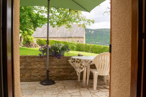 une table et des chaises avec un parasol sur une terrasse dans l'établissement Gîte Gîte La Parro 2/4 personnes, à Cultures