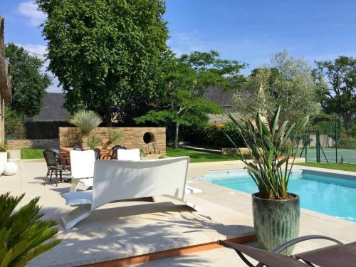 une terrasse avec des chaises blanches et une piscine dans l'établissement Mise au vert, à Grand-Champ
