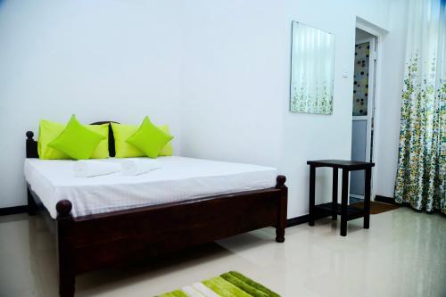a bedroom with a bed with green pillows at Mario Family Villa and Restaurant in Negombo