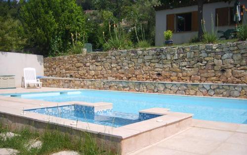 - une piscine avec un mur et un mur en pierre dans l'établissement La cigaline, à Bagnols-en-Forêt