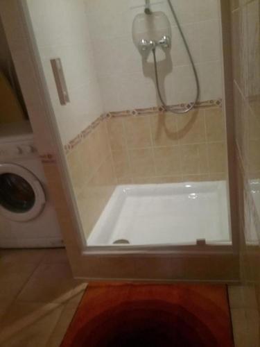 La salle de bains est pourvue d'une baignoire blanche et d'une douche. dans l'établissement La cigaline, à Bagnols-en-Forêt