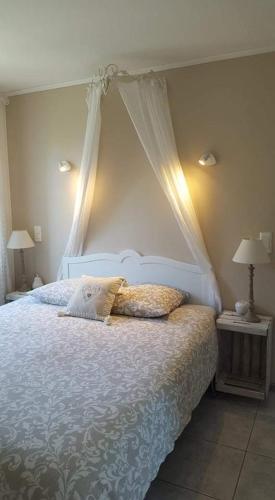 une chambre avec un lit blanc à baldaquin dans l'établissement Le clos des anges, à Gonfaron