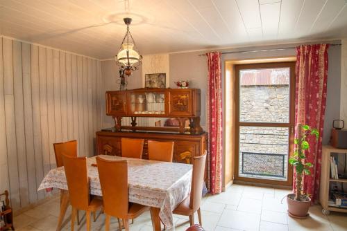 a dining room with a table and chairs and a window at Gîte La Maison Bleue 4/6 personnes in Saint-Étienne-du-Valdonnez
