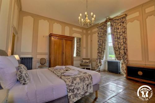 a bedroom with a white bed and a chandelier at Chateau de la giraudais in Mézières-sur-Couesnon