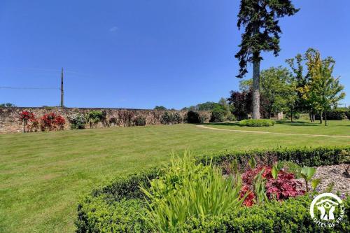 a field of grass with a tree and a wall at Chateau de la giraudais in Mézières-sur-Couesnon