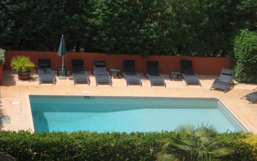 - une piscine avec des chaises et un bouquet de chaises longues dans l'établissement Le marronnier a la bouverie, à Roquebrune-sur Argens
