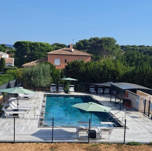 - une piscine avec des parasols, des tables et des chaises dans l'établissement Maison arboree de 39 m2 - piscine et plage a 400m -, à Six-Fours-les-Plages