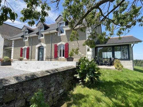 a house with red shutters and a stone wall at Larrouy in Asson