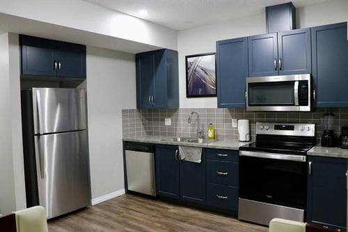 a kitchen with blue cabinets and stainless steel appliances at Parkside Luxury Stay with Xbox Entertainment in Calgary