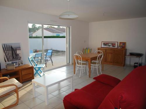 - un salon avec un canapé rouge, une table et des chaises dans l'établissement Maison neuve avec jardin à 300 m du bourg, proche plage, 2 chambres, terrasse, parking, La Tranche-sur-Mer - FR-1-194-78, à La Tranche-sur-Mer