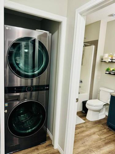 a washer and dryer in a bathroom with a toilet at Parkside Luxury Stay with Xbox Entertainment in Calgary