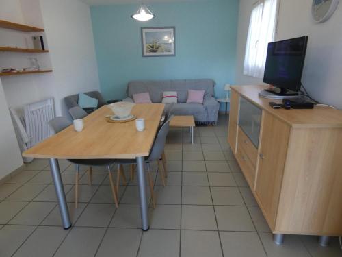 a living room with a table with a television and a couch at Marensin in Mugron