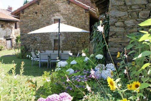 a garden with a table and chairs and an umbrella at Les moissonneurs in Champagnac-la-Rivière