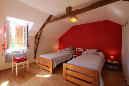 two beds in a room with a red wall at Chez soule in Riupeyrous