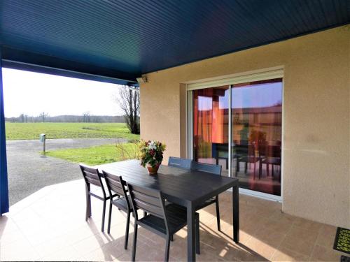 une table noire et des chaises sur une terrasse dans l'établissement Le saoutot, à Saint-Jean-de-Marsacq