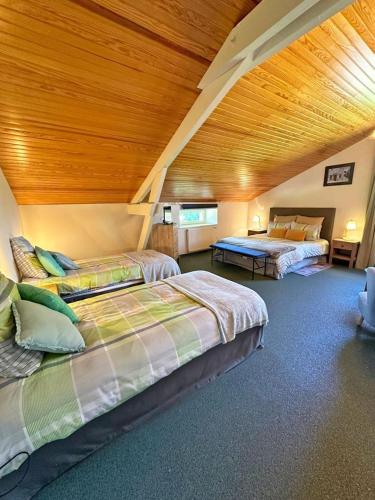 une chambre avec deux lits et un plafond en bois dans l'établissement Aux quatre vents, à Bussière-Galant