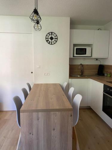 une cuisine avec une table en bois et une horloge au mur dans l'établissement Appartement au pied des pistes, à Saint-François-Longchamp