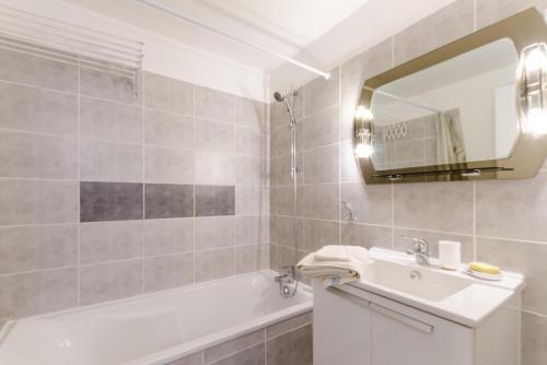 a bathroom with a sink and a tub and a mirror at Clair'omer in Yèvres-le-Petit