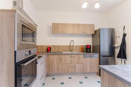 a kitchen with wooden cabinets and stainless steel appliances at Clair'omer in Yèvres-le-Petit