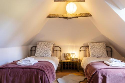 a attic room with two beds and a chandelier at Le gout in Lasseubetat