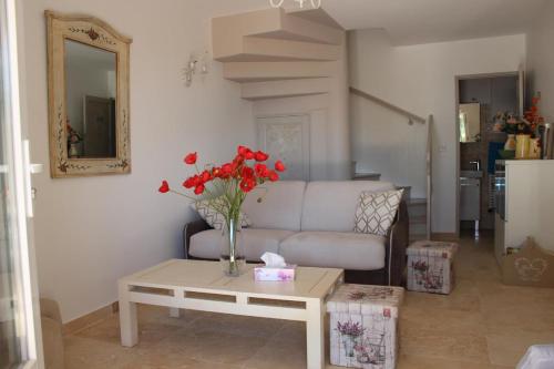 un salon avec un canapé et une table avec des fleurs rouges dans l'établissement Joli gite les palmiers iii, à La Croix-Valmer