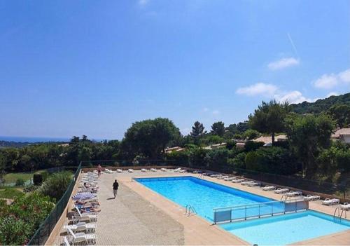 une piscine avec des chaises et une personne debout à côté dans l'établissement Joli gite les palmiers iii, à La Croix-Valmer