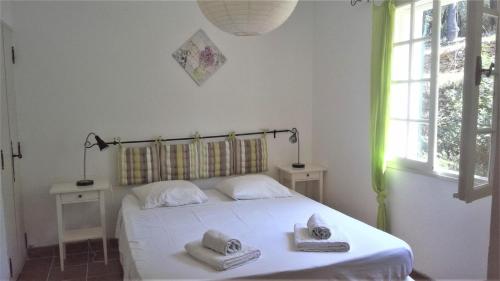 une chambre avec un lit blanc avec des serviettes dessus dans l'établissement Le bastidon des tilleuls, au Beausset