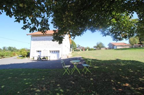 a picnic table and chairs in the shade of a tree at Le picatao, les flamanchies in Saint-Mathieu