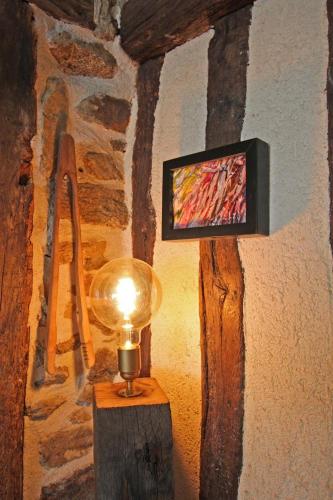 a lamp on a table with a tv on a wall at Chez minetou in Saint-Gence