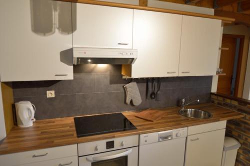 une cuisine avec des armoires blanches et un évier dans l'établissement Les frenes, à Cussac