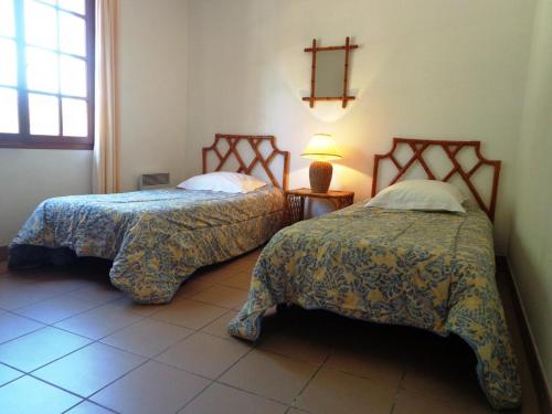 - une chambre avec 2 lits et une lampe au sol carrelé dans l'établissement Les chenes, à Saint-Julien-en-Born