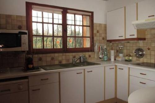 une cuisine avec des armoires blanches, un évier et une fenêtre dans l'établissement Gite 