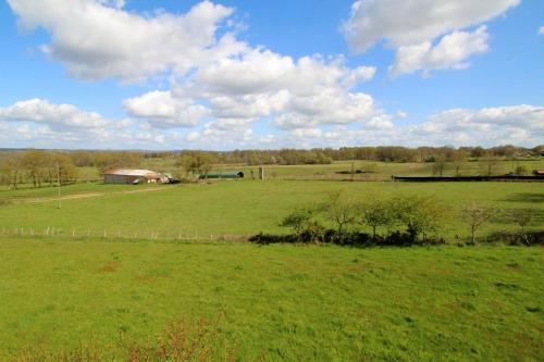 a large green field with a barn in the distance at Bois de l'age in Saint-Auvent