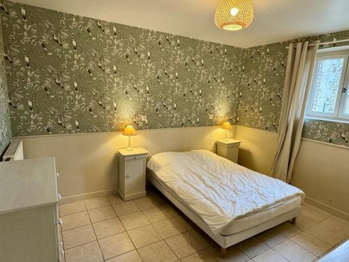a bedroom with a bed and two night stands with lamps at Le jardin in Saint-Priest-Taurion