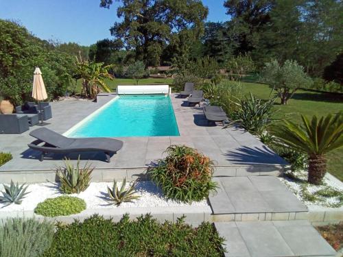 una piscina in un giardino con sdraio e piante di La maison poulet a Soustons