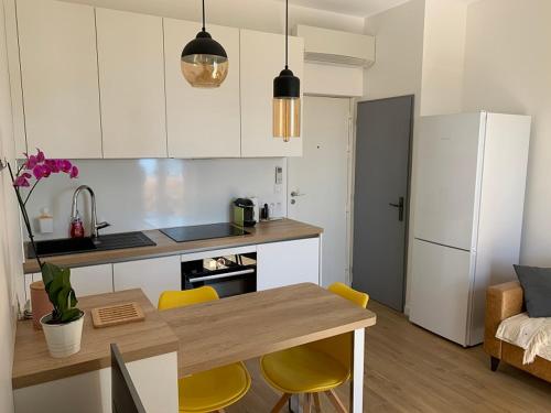 une cuisine avec une table, des chaises et un réfrigérateur dans l'établissement Appartement vue mer, à Bandol