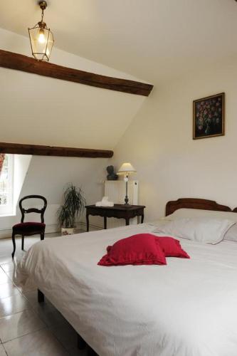 une chambre avec un lit avec un oreiller rouge dessus dans l'établissement Le gite du passage, à Romilly-sur-Seine