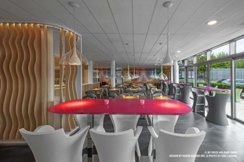 a restaurant with a red table and white chairs at Prize by Radisson, Bremen City in Bremen