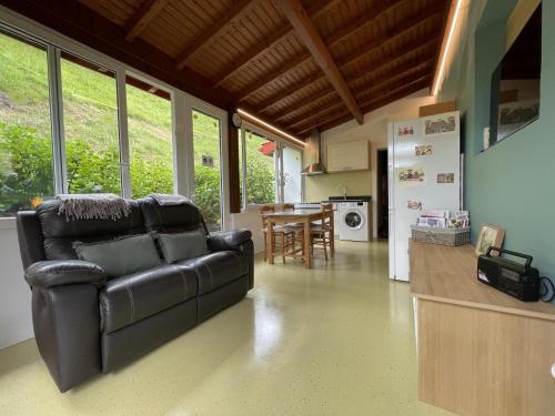 un salon avec un canapé en cuir et une cuisine dans l'établissement Mendi beheria bi, à Uhart-Cize