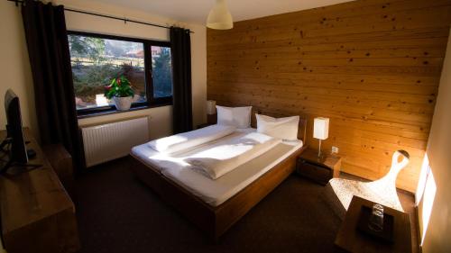 1 dormitorio con 1 cama con pared de madera en Pension Iara, en Arieşeni